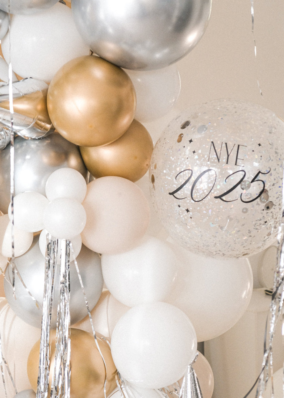 A close up shot of the balloon galrand in shiny silver, gold, white and creams with metallic tinsel and spikey balloon accents against a cream backdrop 