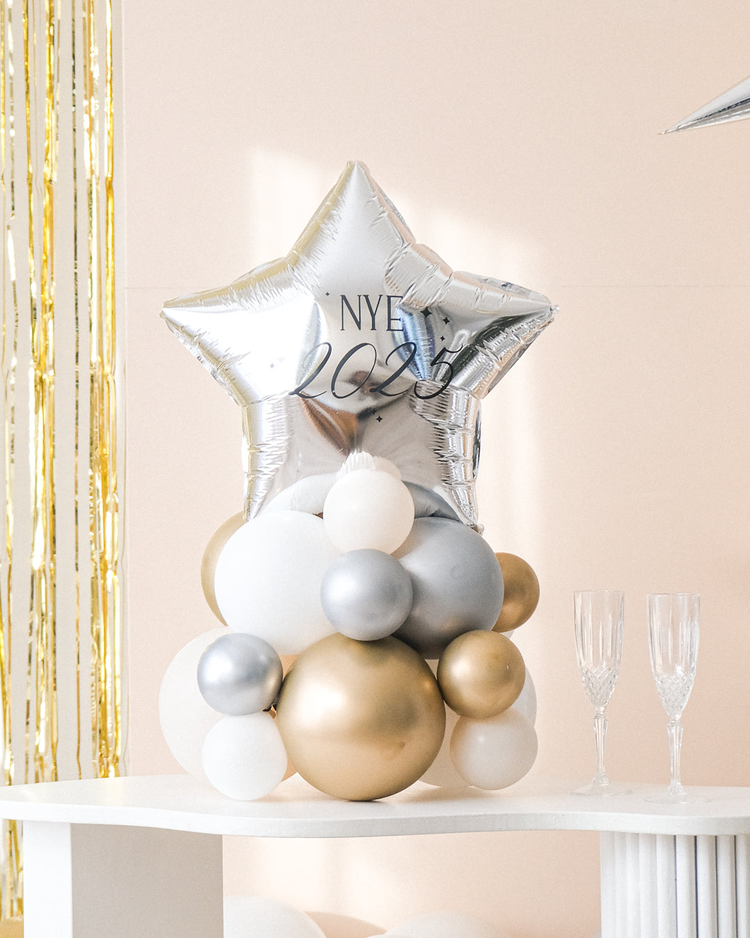 A closer view of the balloon centerpiece featuring a shiny star-shaped balloon, placed on a white table with gold-colored balloons