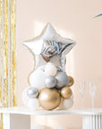 A closer view of the balloon centerpiece featuring a shiny star-shaped balloon, placed on a white table with gold-colored balloons
