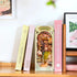 Books on a shelf wiht one 3D minature book shelf decor box. Insdie the box is sakura themed setting with a girl in the middle