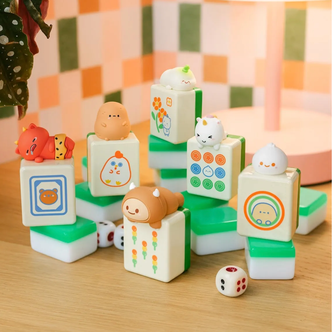 6 mahjong themed vinyl toys with a cute cartoon character on top, on tabletop with colorful wallpaper