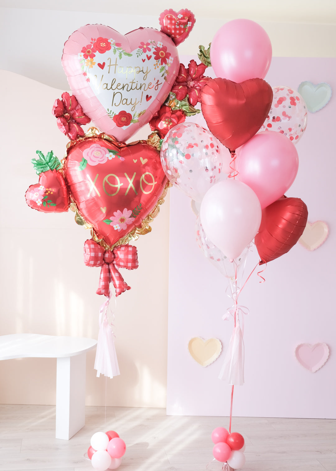 A balloon set with a double stack of floral heart balloons in various shades of red and pink, with bows and mini hearts, designed for Valentine's Day.