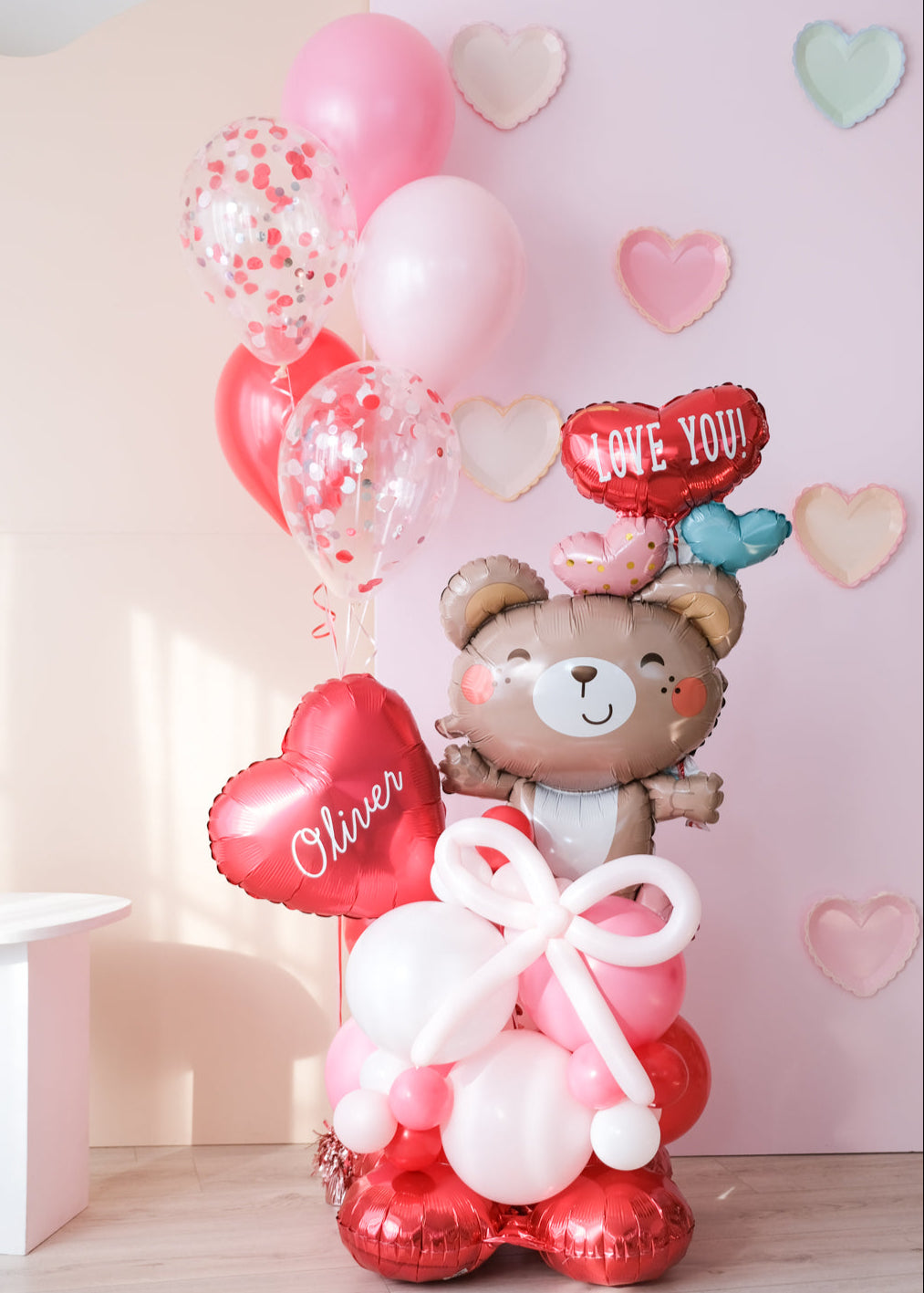 A Valentine's Day balloon present featuring a heart-shaped balloon with the name 'Olivia', a teddy bear holding balloons
