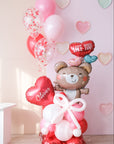 A Valentine's Day balloon present featuring a heart-shaped balloon with the name 'Olivia', a teddy bear holding balloons