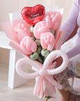 A bouquet of pink balloon roses with a pink balloon bow held by a person