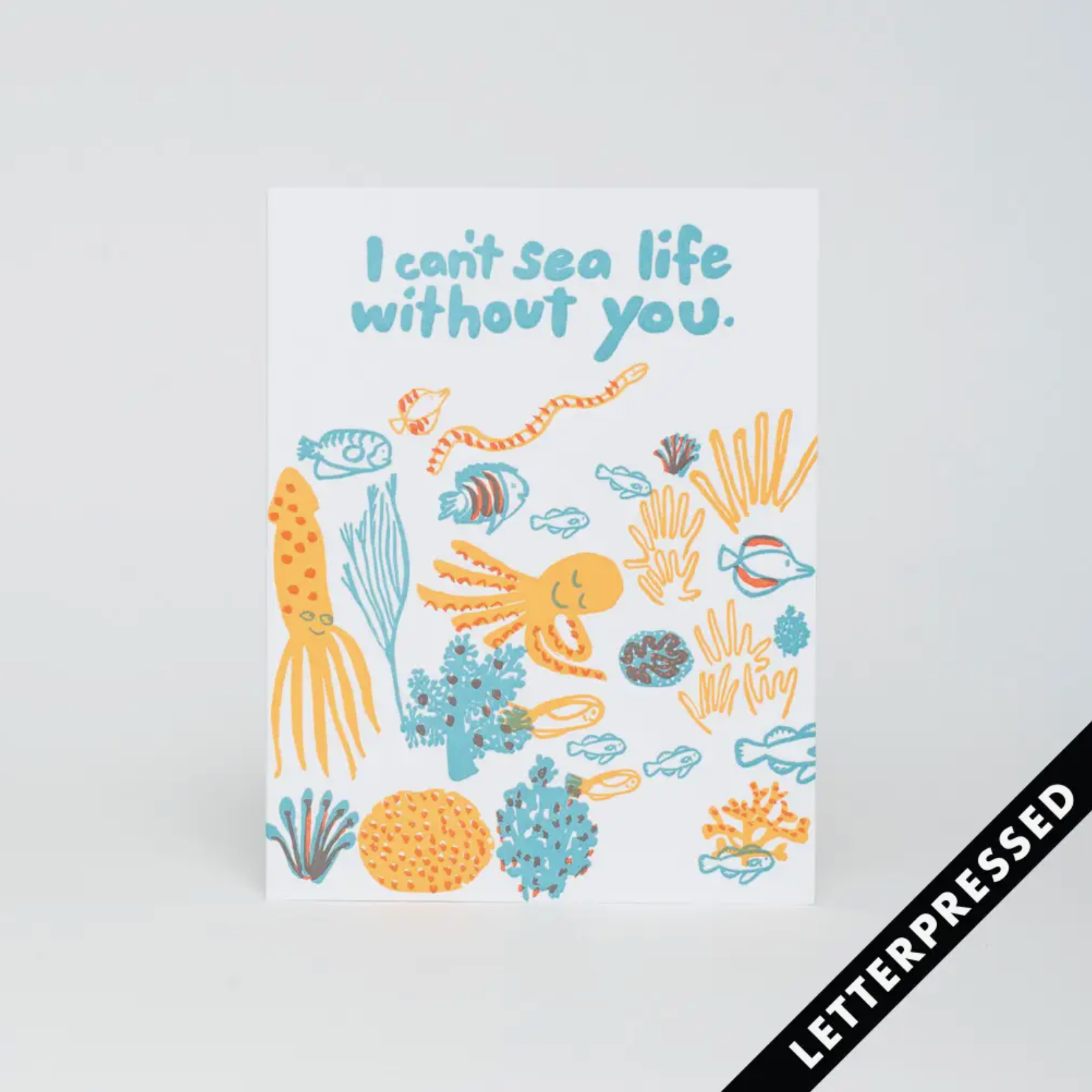 A greeting card with an aquatic theme, featuring a variety of sea creatures and the text 'I CAN'T SEA LIFE WITHOUT YOU' along with a letterpress stamp symbol.