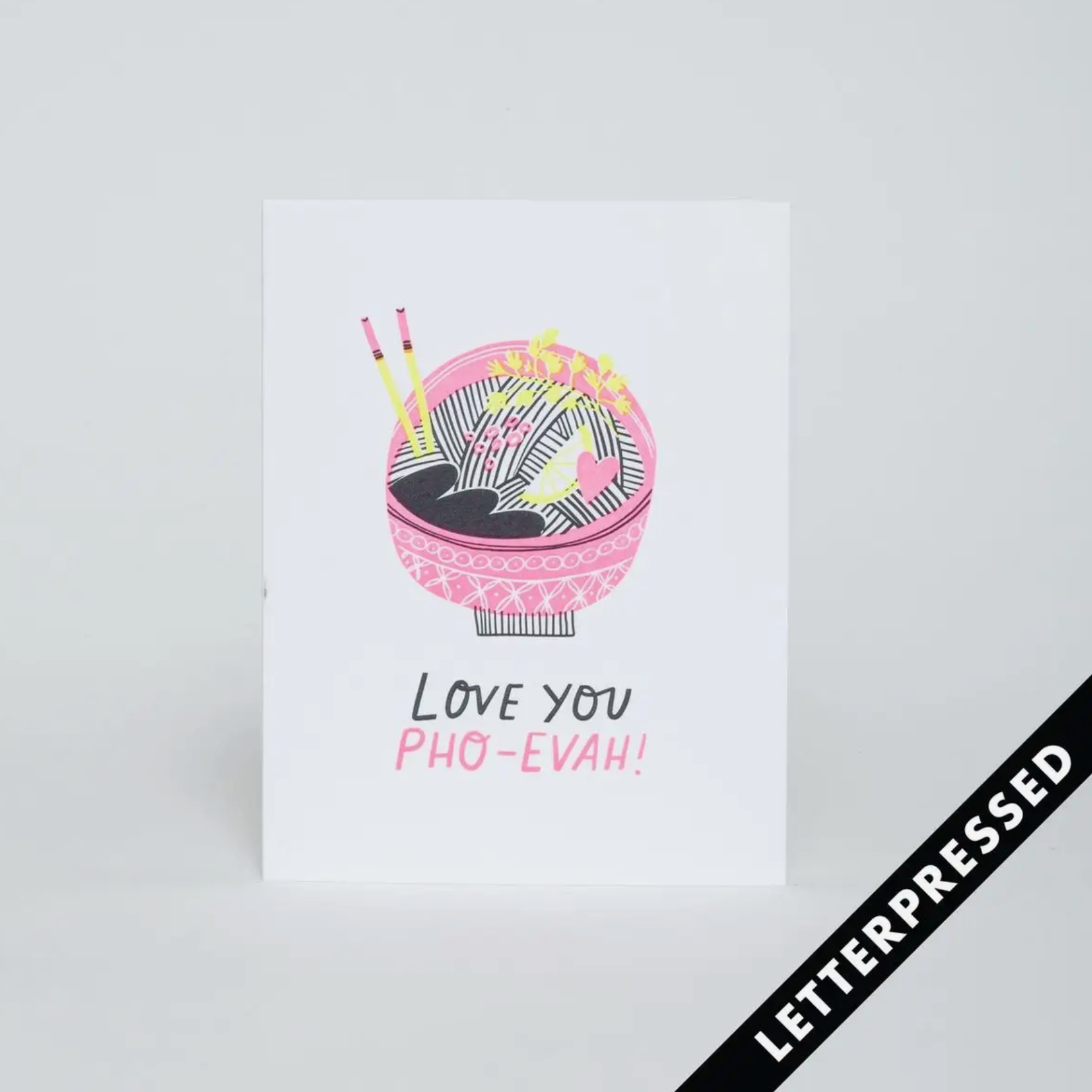 A greeting card with a colorful illustration of a pho bowl and chopsticks, alongside the text 'I love you PHO-EVAH!' enclosed in a heart shape. The card also includes a pink envelope.