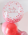 Clear balloon with heart confetti printed and red text "be my valentine"