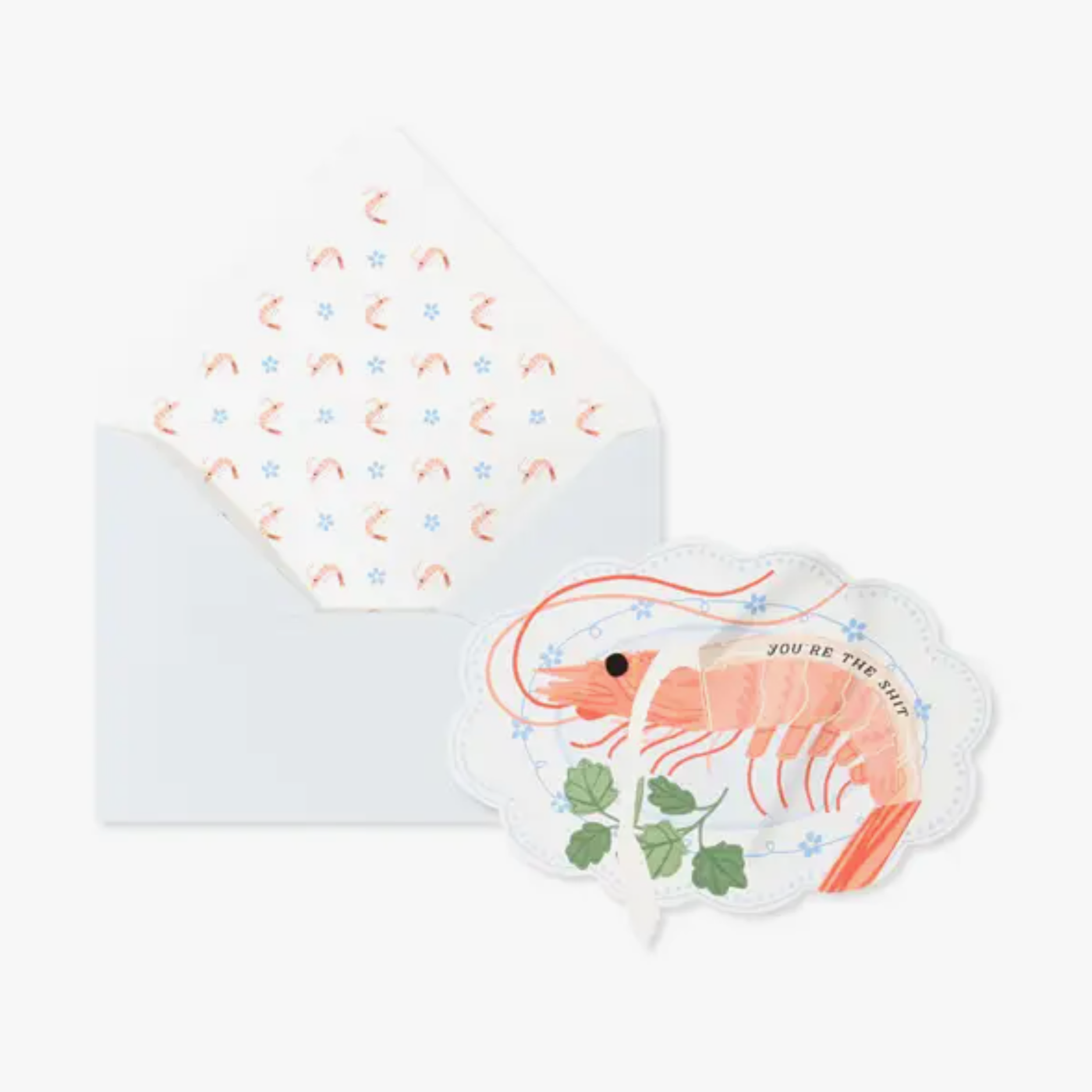 A humorous greeting card with a die-cut shrimp design, accompanied by a powder blue envelope with a printed pattern inside.