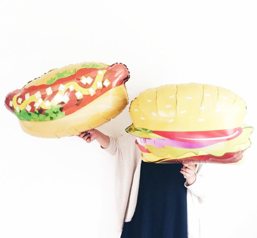 girl holding hotdog and burger balloons