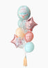 A balloon bouquet featuring a mint-colored orb with a birthday cake design, accompanied by coral confetti balloons, star-shaped foil balloons, and a tassel.